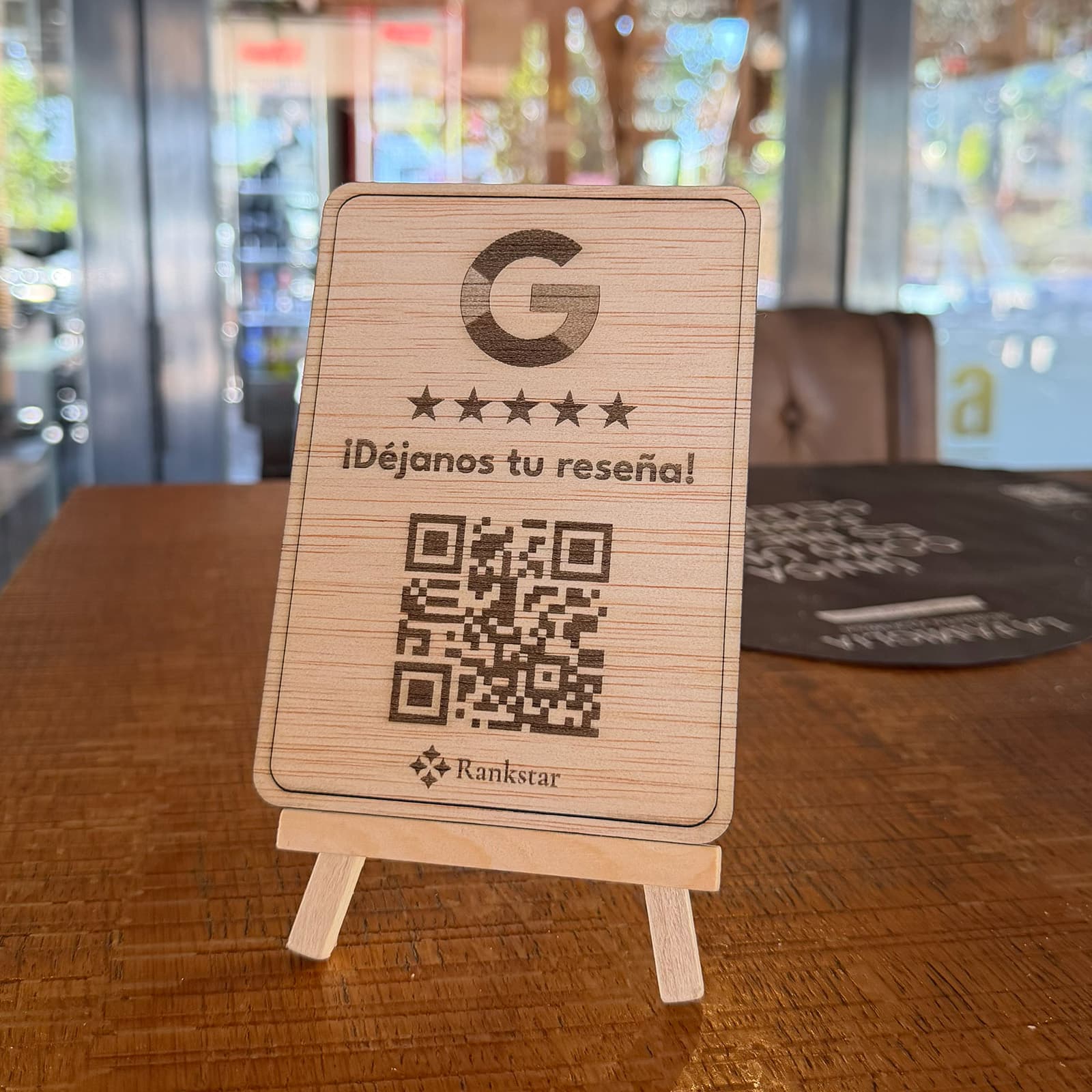 Expositor Rankstar de Google sobre una mesa de madera en el salón de un restaurante, con los ventanales al fondo