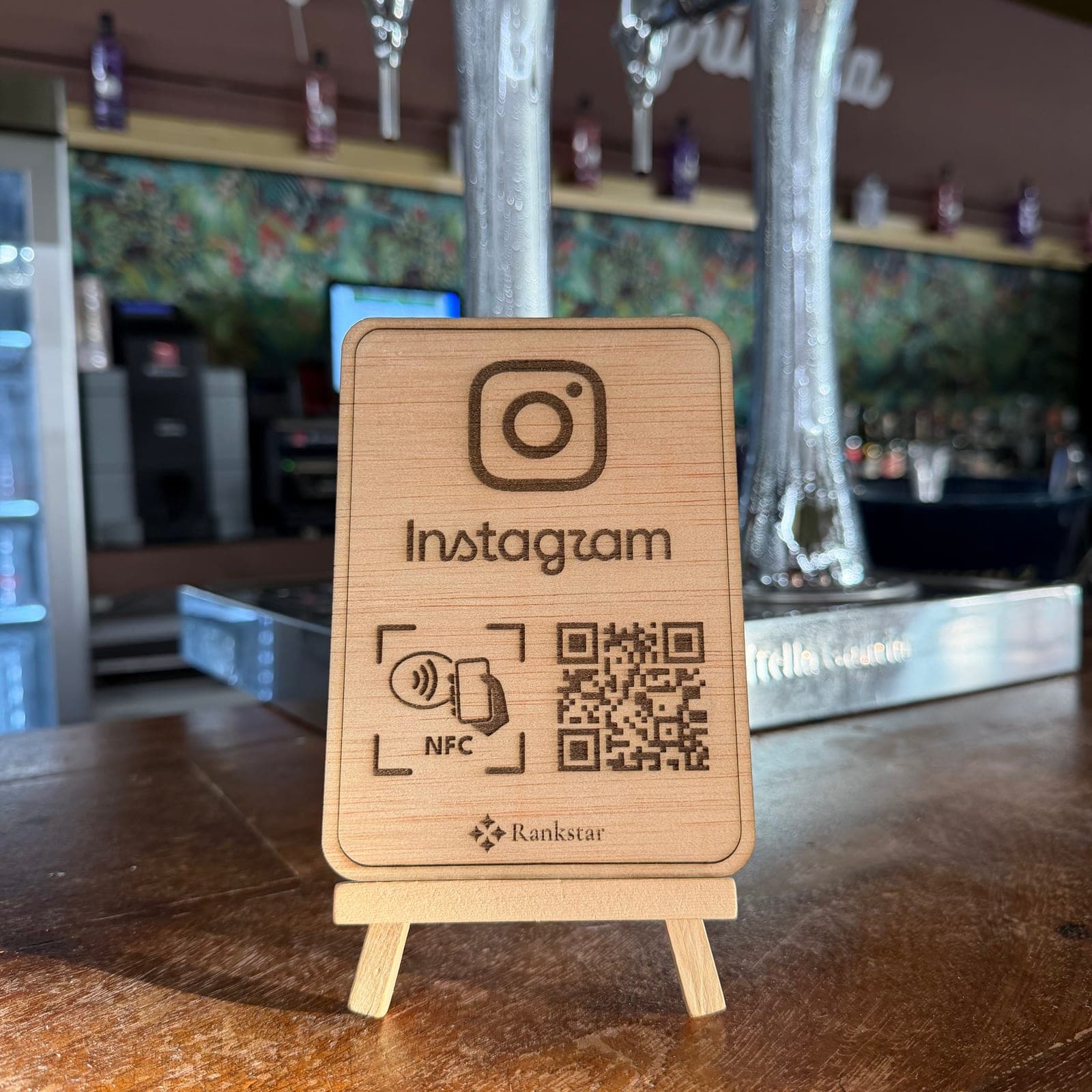 Expositor Rankstar de Instagram en la barra de un bar, con la pared de papel pintado verde detrás