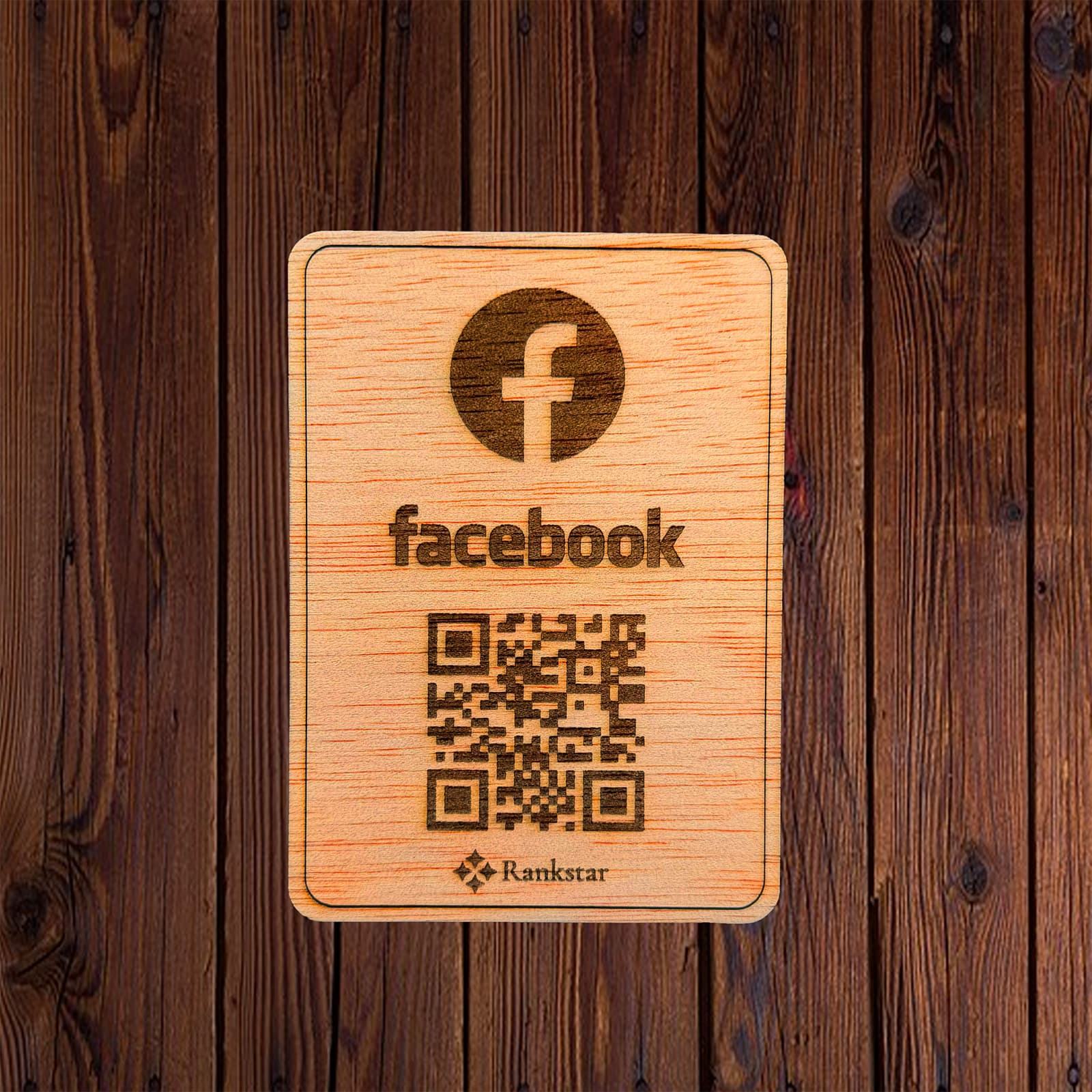 Placa Rankstar de madera con el logo de Facebook y el QR grabado a láser, sobre un fondo de madera oscura