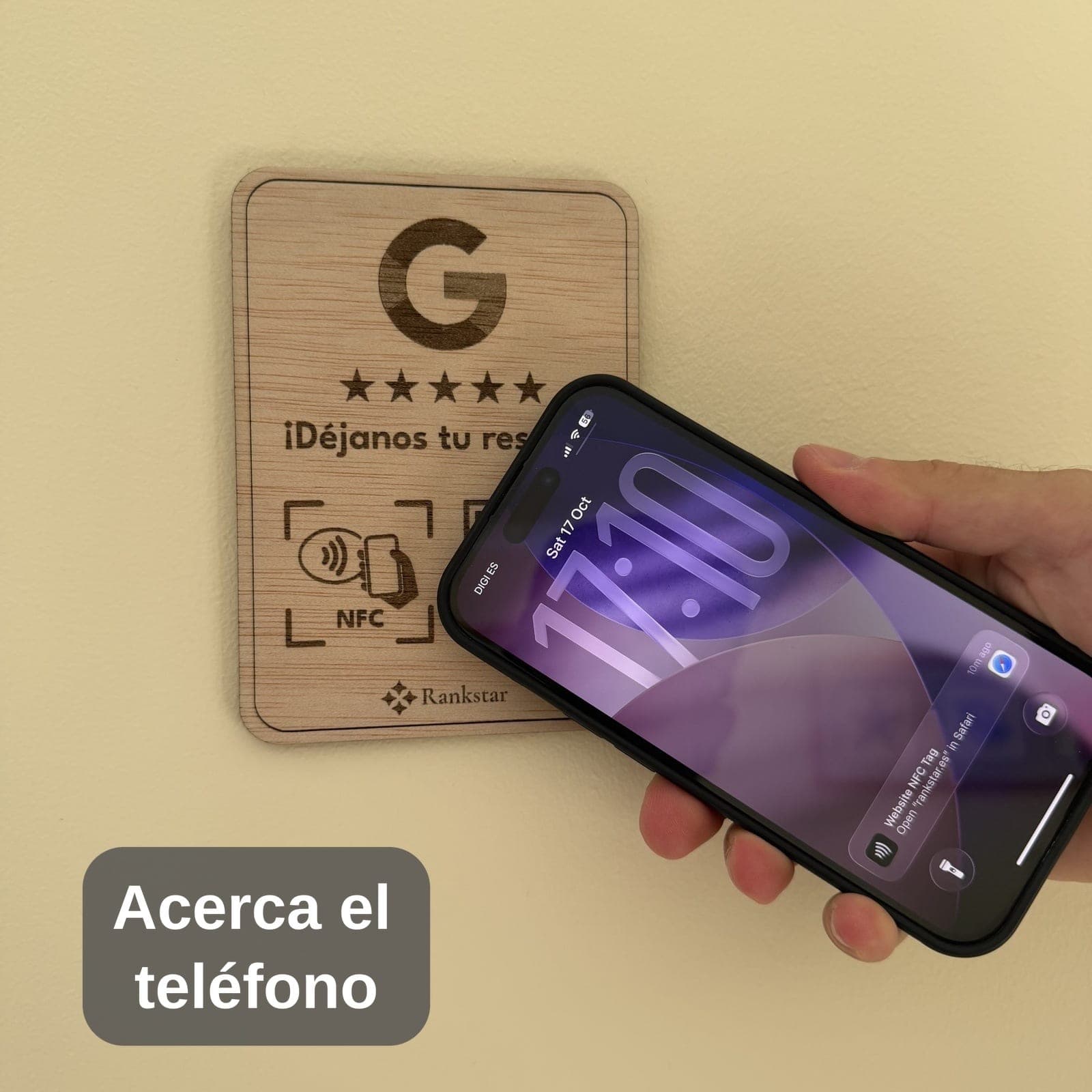 Una mano acerca el móvil a la placa Rankstar de Google pegada en una pared, con el rótulo «Acerca el teléfono»