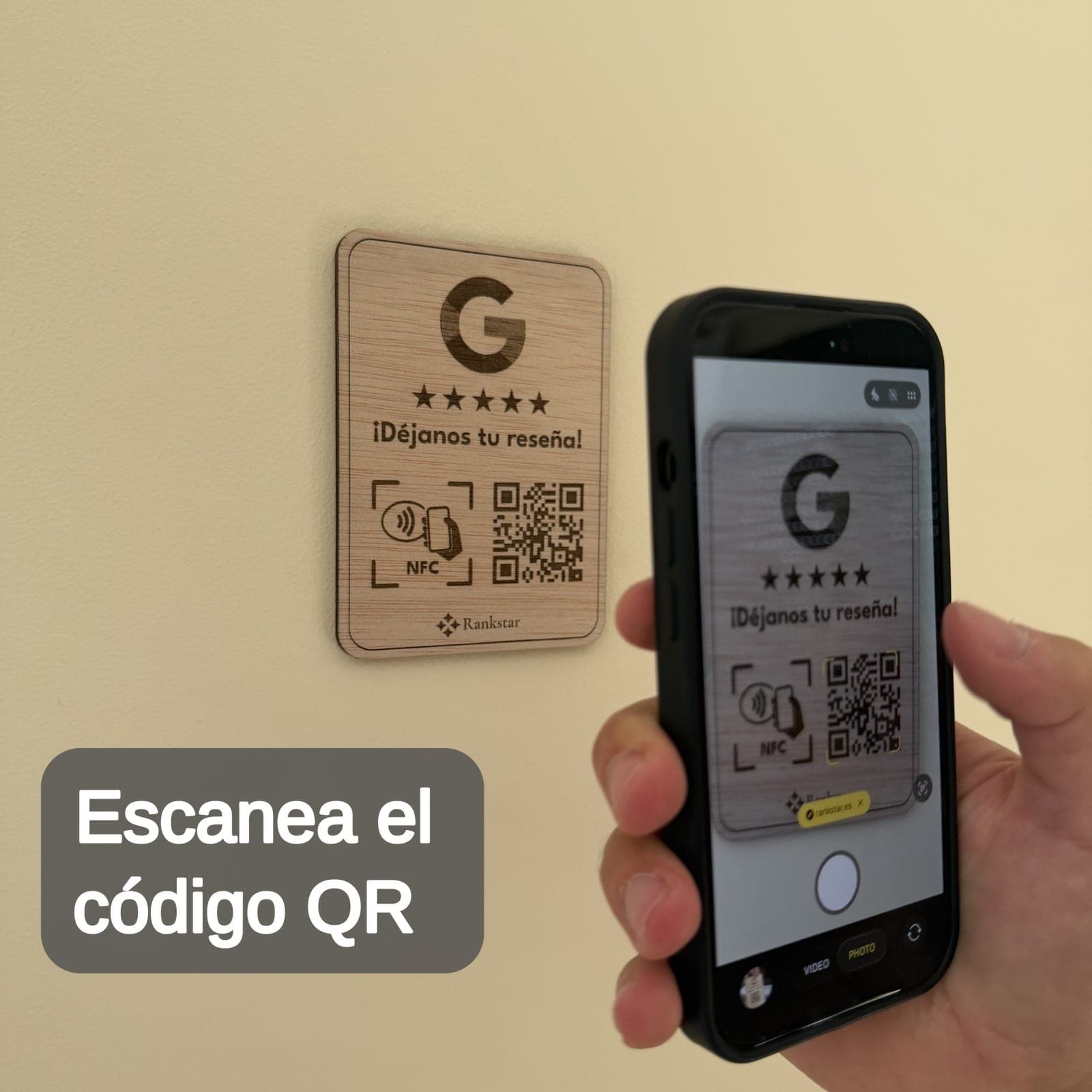 Una mano escanea con el móvil el QR de la placa Rankstar de Google pegada en una pared, con el rótulo «Escanea el código QR»