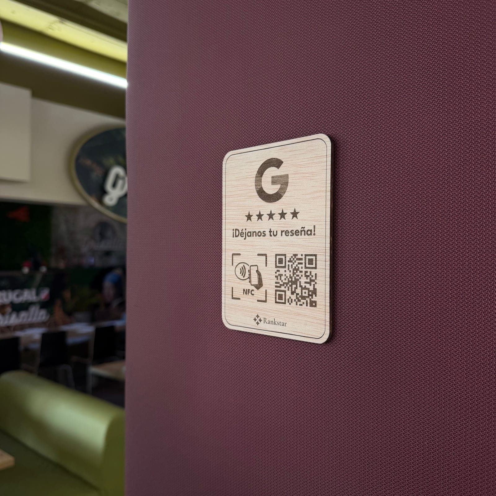 Placa Rankstar de reseñas de Google pegada en la pared granate de un restaurante