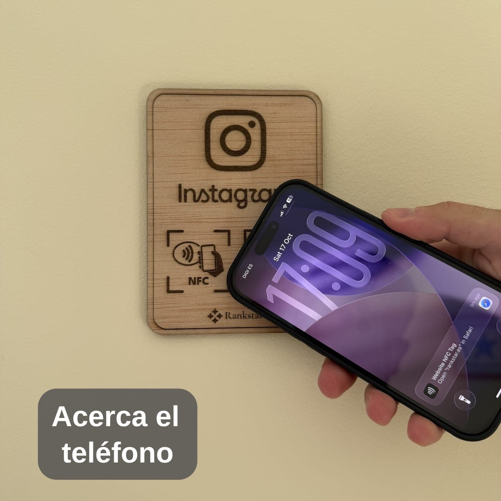 Una mano acerca el móvil a la placa Rankstar de Instagram pegada en una pared, con el rótulo «Acerca el teléfono»