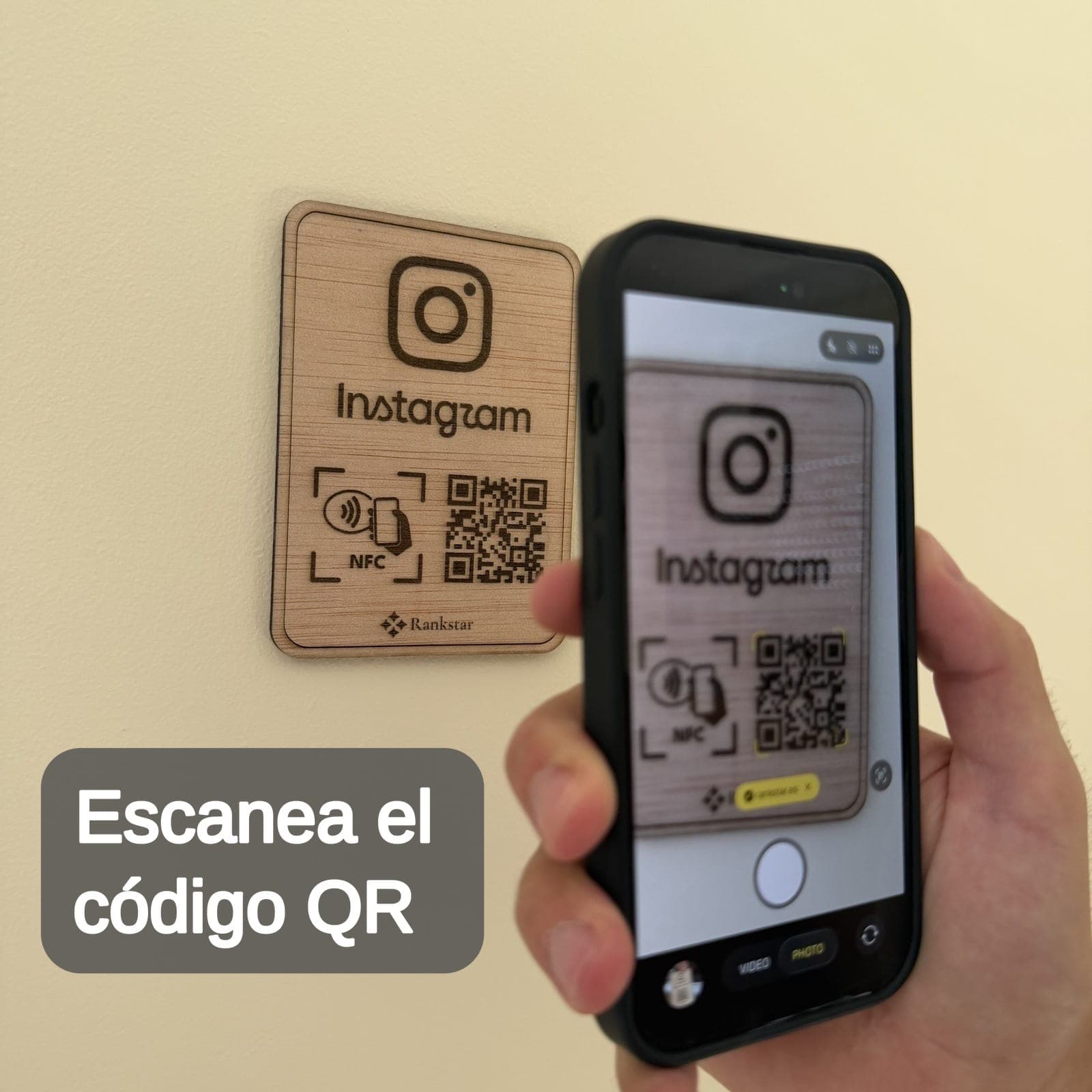 Una mano escanea con el móvil el QR de la placa Rankstar de Instagram pegada en una pared, con el rótulo «Escanea el código QR»