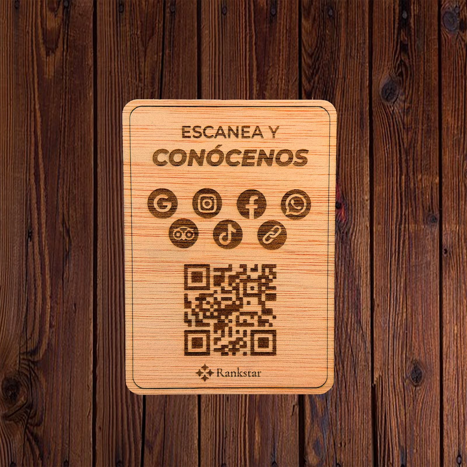 Placa Rankstar de madera con el rótulo «Escanea y conócenos», los iconos de Google, Instagram, Facebook, WhatsApp, Tripadvisor y TikTok, y el QR grabado a láser, sobre un fondo de madera oscura