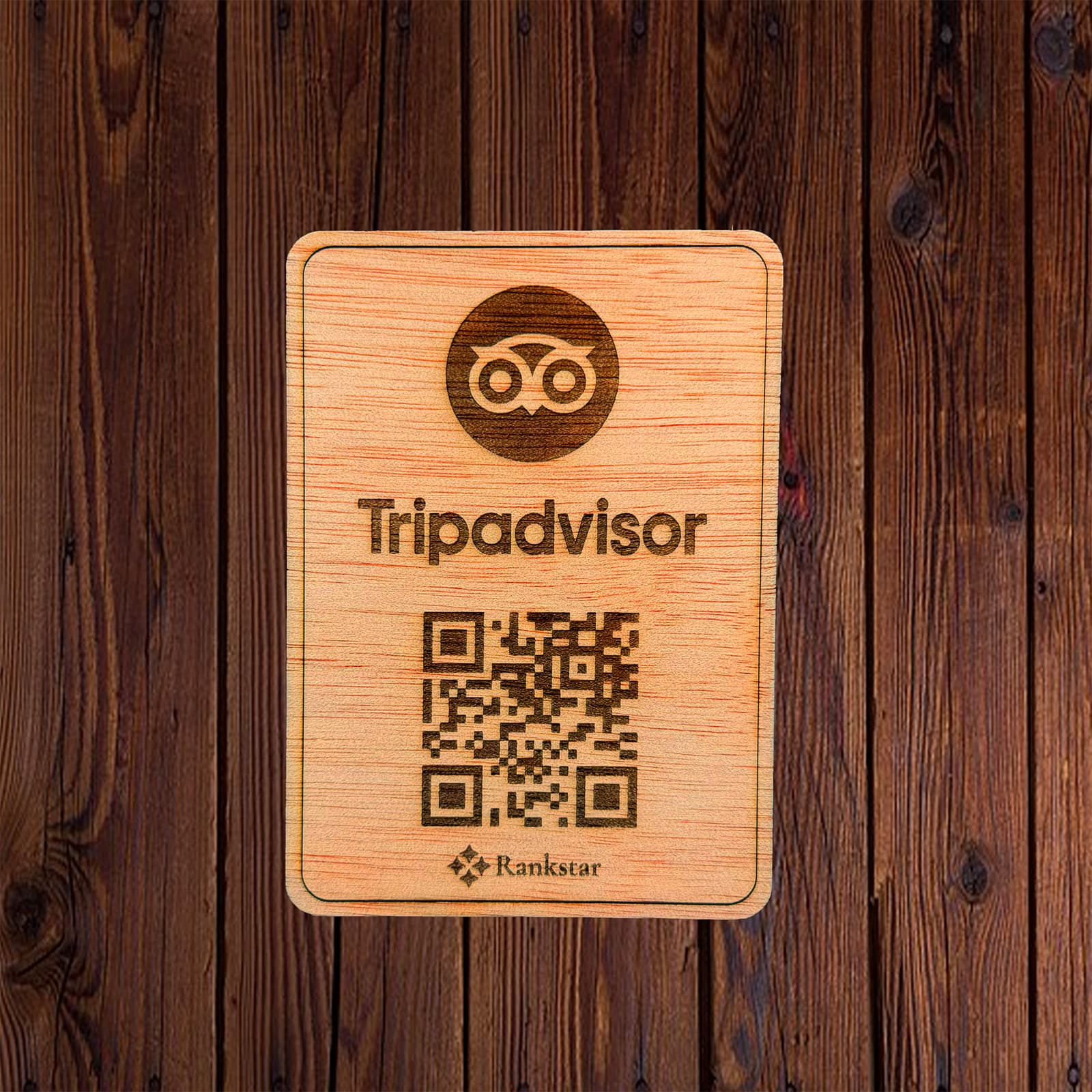 Placa Rankstar de madera con el logo de Tripadvisor y el QR grabado a láser, sobre un fondo de madera oscura