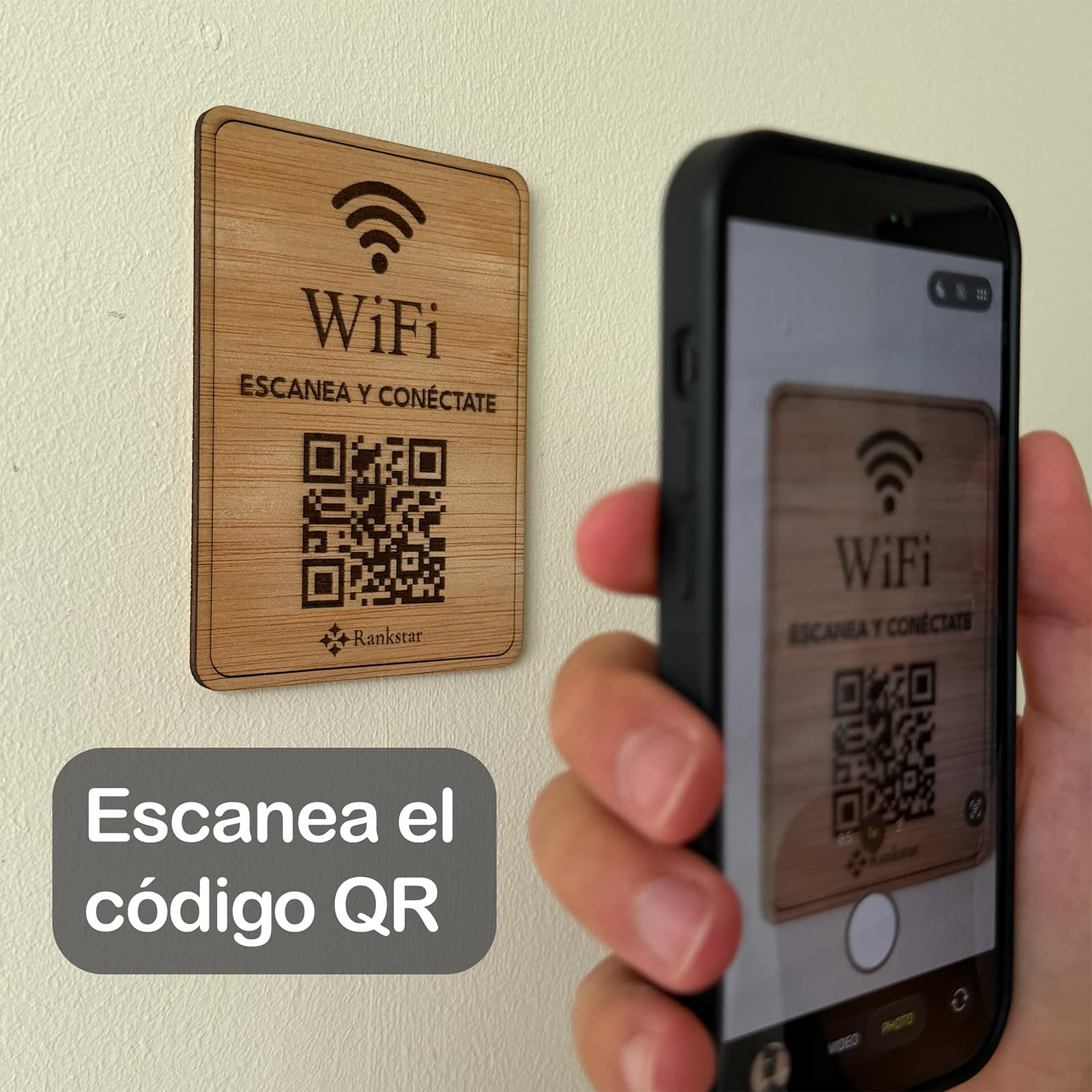 Una mano escanea con el móvil el QR de la placa Rankstar de WiFi pegada en una pared, con el rótulo «Escanea el código QR»